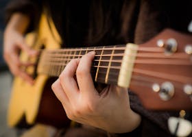 Close view of fingers strumming an acoustic guitar, capturing the essence of music creation.